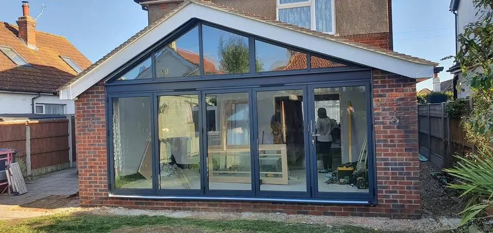 Gable-ended conservatory with dark grey bi-fold doors and glazed roof panels on a brick house