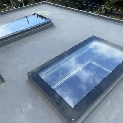 Flat roof rooflight set into a grey roof, reflecting the sky
